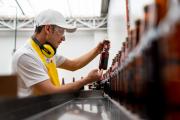 Man supervising the operation of a bottling machine at a brewery