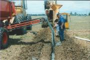 two men backfilling collector drain with blue metal