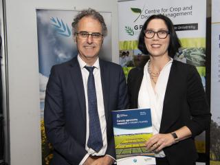 Man and woman holding booklet in front of grains posters