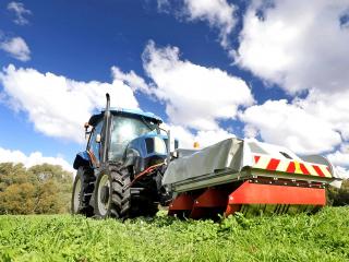 A tractor in a weedy paddock with a brace with flaps on the front.