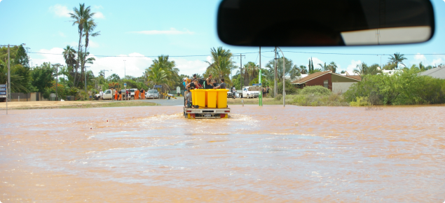 View from a vehicle driving through flood waters in a country town