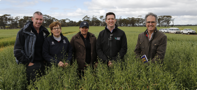 Group of five people standing in an oats paddock on a cold day.