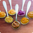 Spoons of baby food in variety of flavours
