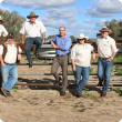 Cattle producers leaning against fence on a farm